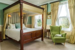 ein Schlafzimmer mit einem Himmelbett und einem grünen Stuhl in der Unterkunft Oldfields House in Bath