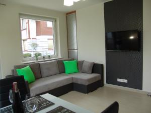 a living room with a couch with green pillows at Apartament Białe Piaski in Dębki