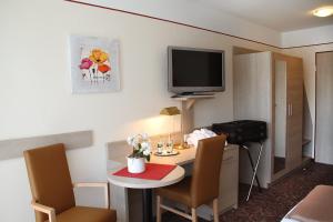 ein Hotelzimmer mit einem kleinen Tisch und einem TV in der Unterkunft Pension Maximilian in Bad Füssing