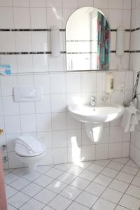 a white bathroom with a sink and a toilet at Hotel Hirsch in Rothenberg