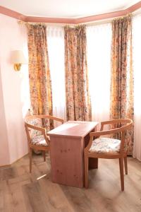 a table and two chairs in a room with windows at Hotel Hirsch in Rothenberg