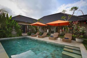a pool with chairs and umbrellas next to a house at Satori Villas Bali in Ubud