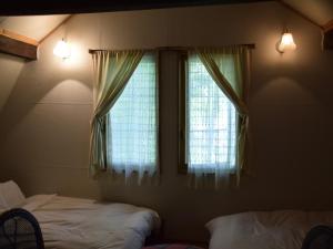 中富良野町的住宿－多克卡農家樂，一间卧室设有2扇窗户,配有窗帘和床