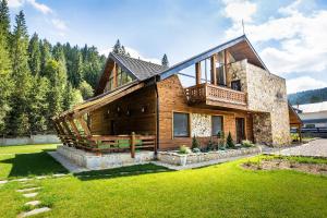 ein großes Holzhaus mit einem Balkon auf einer Wiese in der Unterkunft Bio Valeputna in Valea Putnei