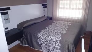 1 dormitorio con 1 cama con manta blanca y negra en Hotel El Millón, en Viveiro