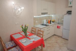 une petite cuisine avec une table, une table rouge et des chaises dans l'établissement Cathedral Apartment, à Lviv