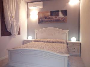 1 dormitorio con 1 cama blanca y 2 mesitas de noche en B&B Martina, en Agugliaro