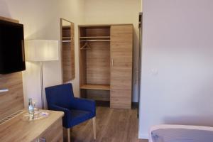 a room with a bedroom with a blue chair and a desk at Stichwehs Hotel am Bahnhof in Elze