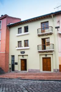 un edificio blanco con puertas y ventanas de madera en Hotel Casa Ecuatreasures Centro Historico en Quito