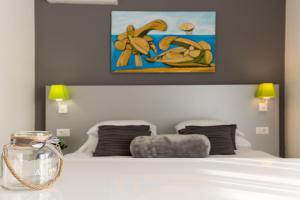 a bedroom with a white bed with a painting on the wall at Villa Liburnum in Zadar