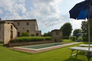 蒙特里久尼的住宿－Agriturismo Tre Madonne，一座花园,花园内设有游泳池和遮阳伞,毗邻一座建筑