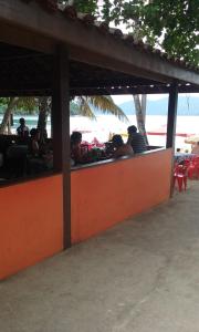 a group of people sitting at a restaurant on the beach at Calumar Guest House in Ubatuba