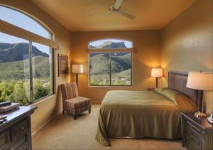 ein Schlafzimmer mit einem Bett und einem Stuhl sowie zwei Fenstern in der Unterkunft Casitas at Sabino Springs in Tucson