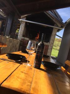 Guest House Aurora في بولجاناك: زجاجة من النبيذ وكأس على طاولة خشبية