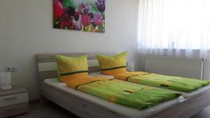 ゼールバッハにあるSchöne Aussichtのベッドルーム1室(緑と黄色の枕が備わるベッド1台付)