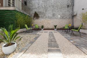 a patio with green chairs and tables in a building at The Well Luxury Rooms in Zadar