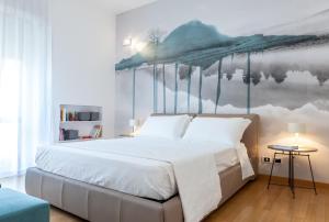 a bedroom with a large white bed with a painting on the wall at Dimore Romano in Lecce