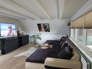 a living room with a couch and a flat screen tv at Surfers lounge in Hvide Sande