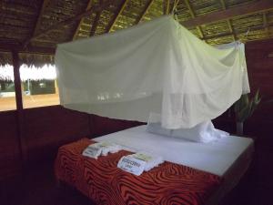 a bed with a white canopy and two towels at Ecolucerna Lodge Tambopata in Puerto Maldonado
