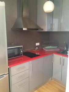 a kitchen with a red counter top with a microwave at Apartamentos San Pablo in Málaga