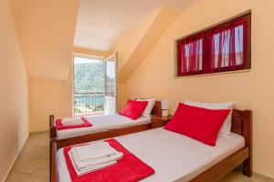Cette chambre dispose de 2 lits avec des oreillers rouges et d'une fenêtre. dans l'établissement Apartments Feniks, à Kotor