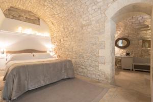 1 dormitorio con cama y pared de piedra en Locanda Don Serafino Historical Boutique Hotel, en Ragusa