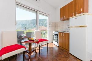 une cuisine avec une table, des chaises et un réfrigérateur dans l'établissement Apartments Feniks, à Kotor