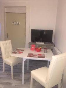 einen weißen Esstisch mit 2 Stühlen und einem TV in der Unterkunft Apartments Center Colmar 5 in Colmar