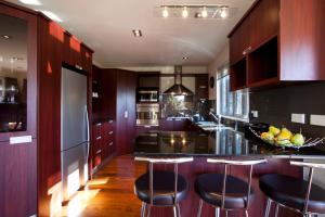 eine Küche mit dunklen Holzschränken und Barhockern in der Unterkunft White Peaks Villa in Queenstown
