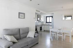 バレンシアにあるApartUP Patacona Horizonのリビングルーム(グレーのソファ付)、キッチンが備わります。