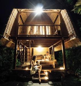 a man and woman sitting in front of a house at Sukanusa Luxury Huts in Nusa Lembongan