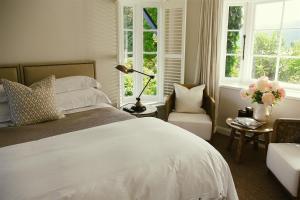 a bedroom with a bed and a chair and windows at Ngamihi Lodge in Rotorua