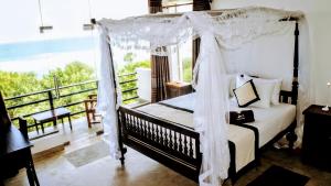 a bedroom with a canopy bed and a balcony at Mirissa Gate in Mirissa