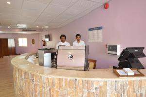 two men standing behind a counter in a waiting room at Al Ahmadi Plaza Resort in Yanbu