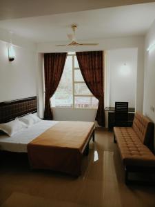 a bedroom with a bed and a couch and a window at M3 Homes in Munnar