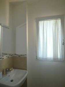 uma casa de banho com um lavatório branco e uma janela em La Casetta em Tavullia