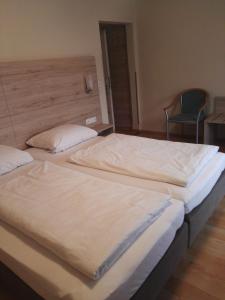 two twin beds in a room with a chair at Hotel Gasthof Momm in Brunnthal