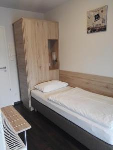 two beds in a room with a wooden headboard at Hotel Gasthof Momm in Brunnthal