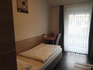 a small bedroom with a bed and a window at Hotel Gasthof Momm in Brunnthal