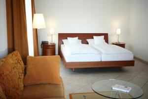 a bedroom with a bed and a couch and a glass table at Maifeld Sport- und Tagungshotel in Werl