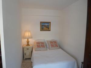 ein kleines weißes Schlafzimmer mit einem Bett und einer Lampe in der Unterkunft Résidence Le Président - Forville in Cannes