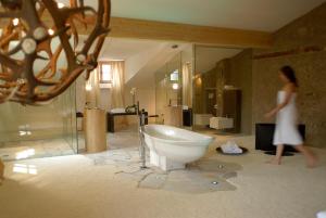 a woman walking in a bathroom with a bath tub at Grottnerhof in Völs am Schlern