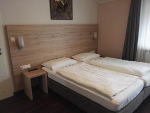 a bedroom with a large bed with a wooden headboard at Hotel Gasthof Momm in Brunnthal