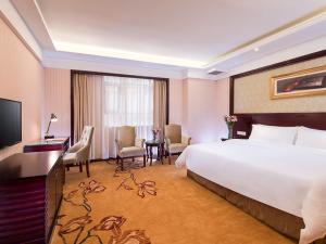 a hotel room with a large bed and a desk at Vienna 3 Best Hotel Guangzhou Zengcheng Xintang Harbour Avenue in Zengcheng