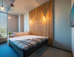 sypialnia z łóżkiem z drewnianą ścianą w obiekcie Urbihop Hotel w Wilnie