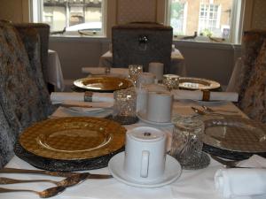 a table with plates and silverware on a table at Jessop House in Tewkesbury