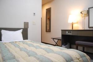 糸魚川市にあるホテルルートイン糸魚川のベッド、ドレッサー、デスクが備わる客室です。