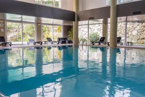 uma grande piscina com cadeiras num edifcio em Pural - Wool Valley Hotel & SPA na Covilh