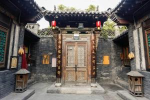una entrada a un edificio con puerta de madera en Pingyao Laochenggen Inn, en Pingyao