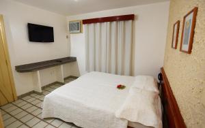 Un dormitorio con una cama blanca con una flor. en Marlim Porto Hotel, en Porto Seguro